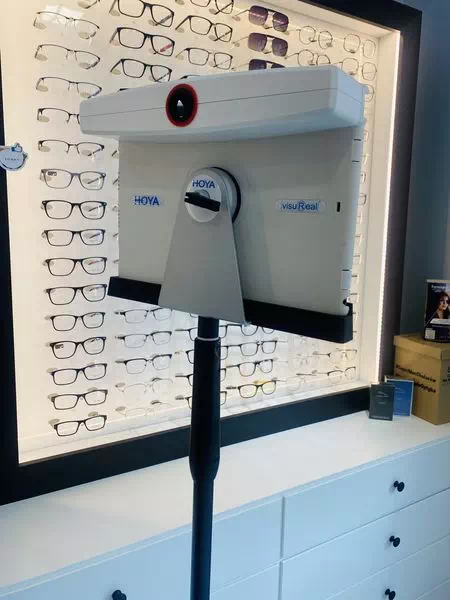 komputer na stojaku na tle ściany z okularami